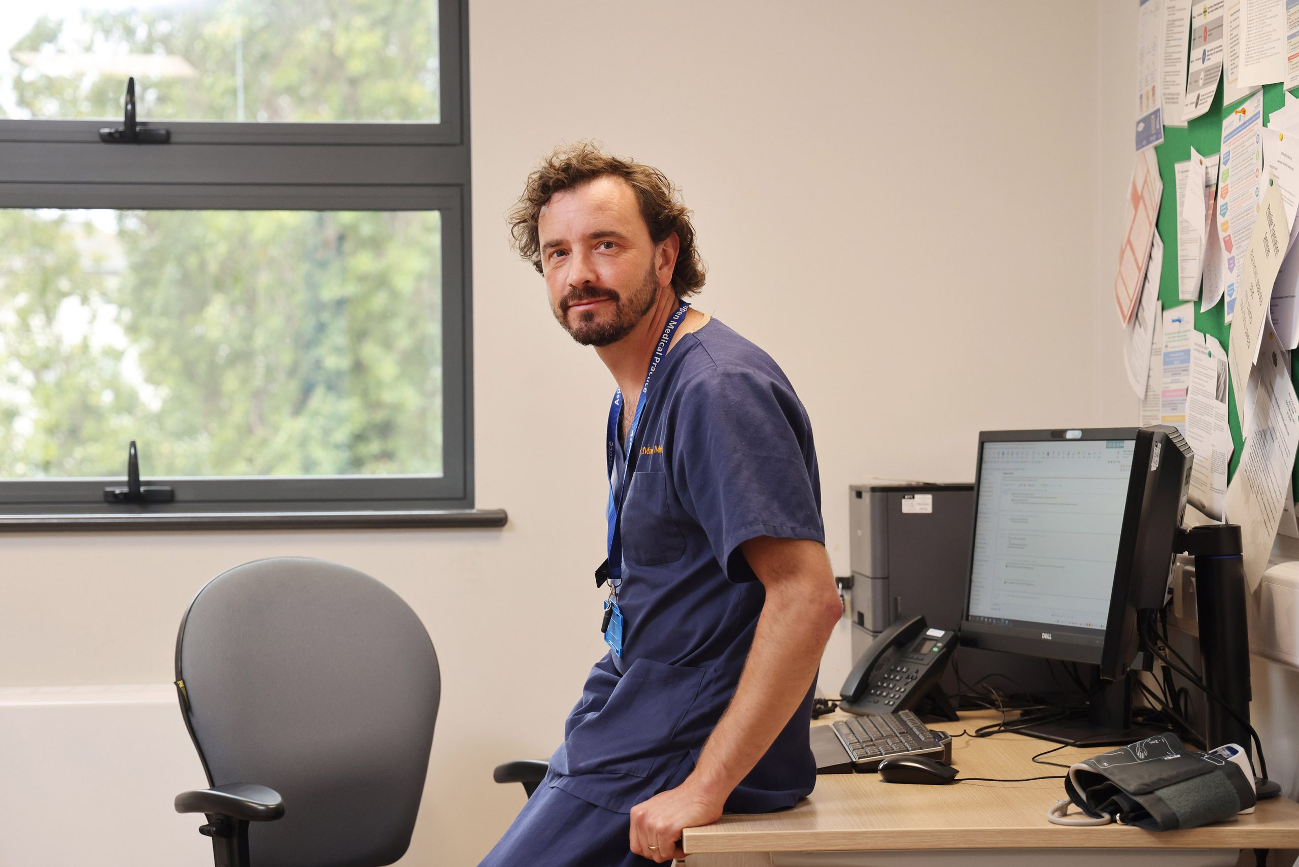 GP standing in modern consultation room.